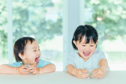 笑顔で水を飲む子ども達の写真
